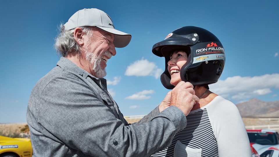 A man helps a student fasten her helmet.