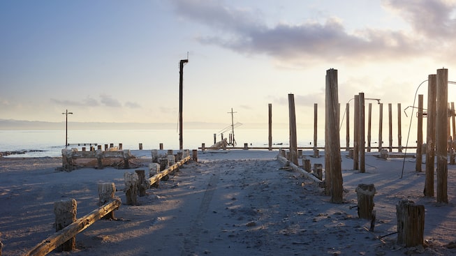 The sand-covered road leading into Salton Sea, California, ends at the posts of a long-gone pier.