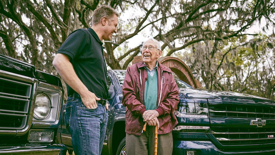 Eric Stanczak y Paul Hitch están parados hablando entre dos camionetas Chevy.