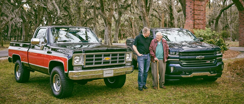 Eric Stanczak y Paul Hitch están parados hablando entre una camioneta Chevy clásica y una Chevy Silverado Centennial Edition.