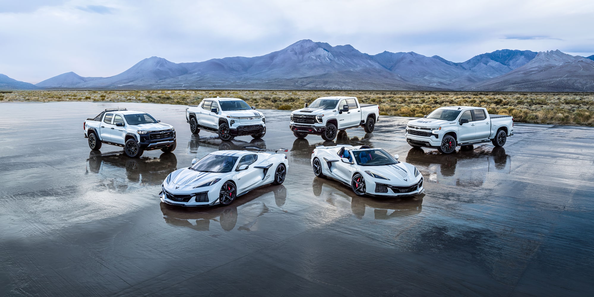 A Collection of Chevrolet Stars and Steel Edition Corvettes and Trucks on a Wet Surface in a Desert.
