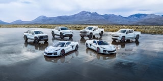 A Collection of Chevrolet Stars and Steel Edition Corvettes and Trucks on a Wet Surface in a Desert.