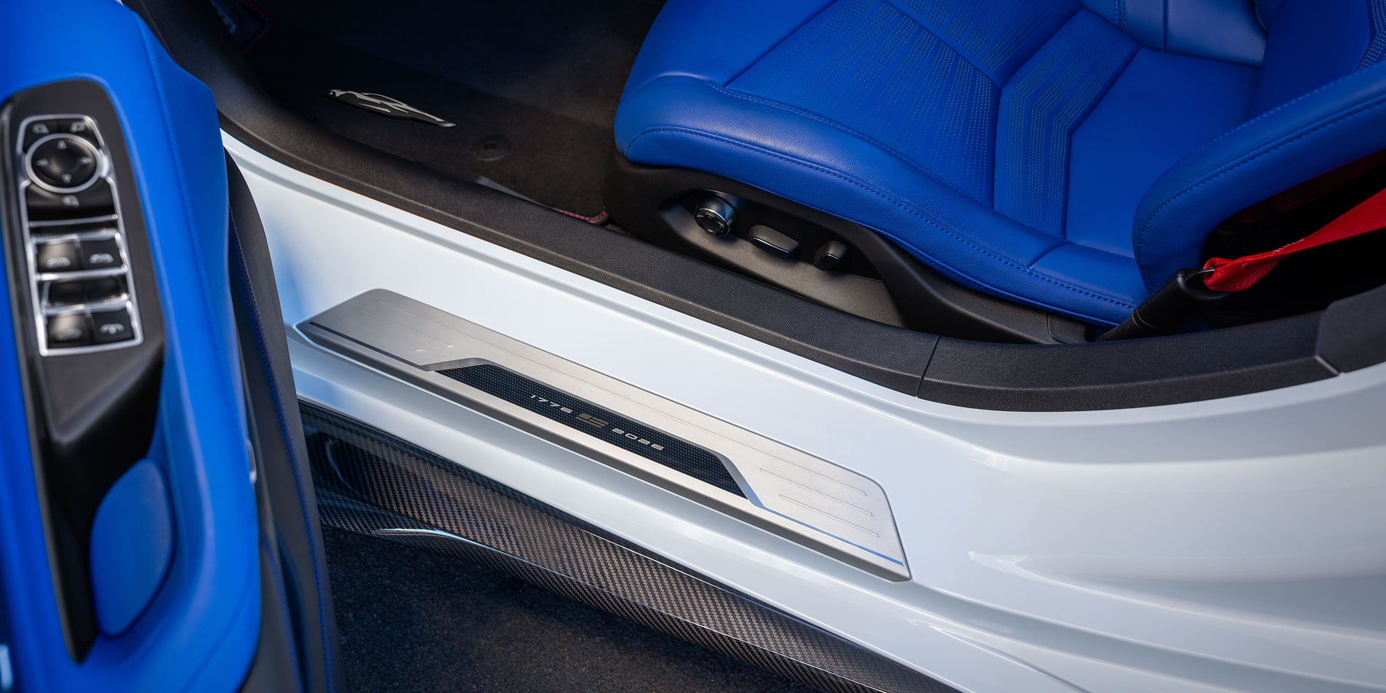 A Close-Up View Of A White Chevrolet Interior Door Sill And Bright Blue Leather Seat With Contrasting Black Trim.