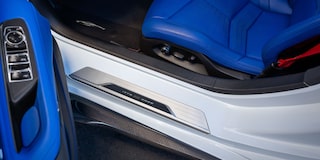 A Close-Up View Of A White Chevrolet Interior Door Sill And Bright Blue Leather Seat With Contrasting Black Trim.