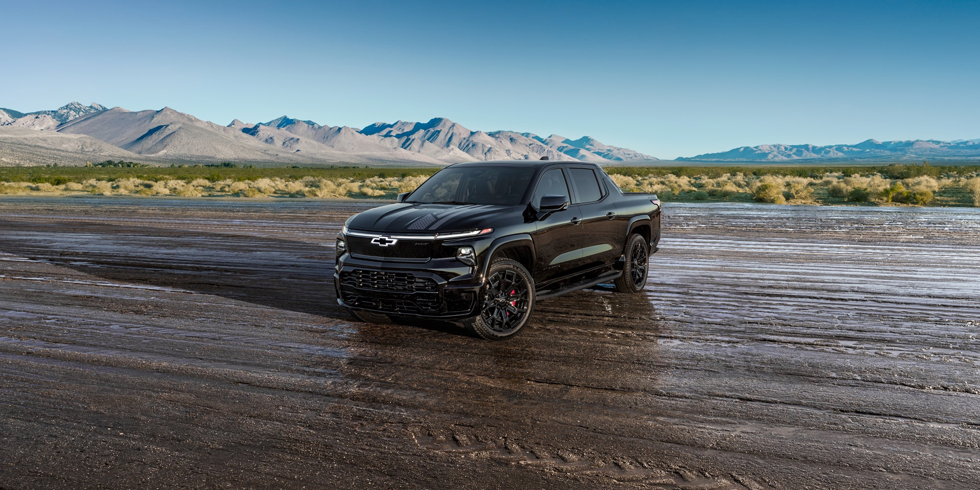 A Black Chevrolet Silverado EV Stars and Steel Edition Truck Parked on a Wet Dirt Road.