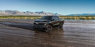 A Black Chevrolet Silverado EV Stars and Steel Edition Truck Parked on a Wet Dirt Road.