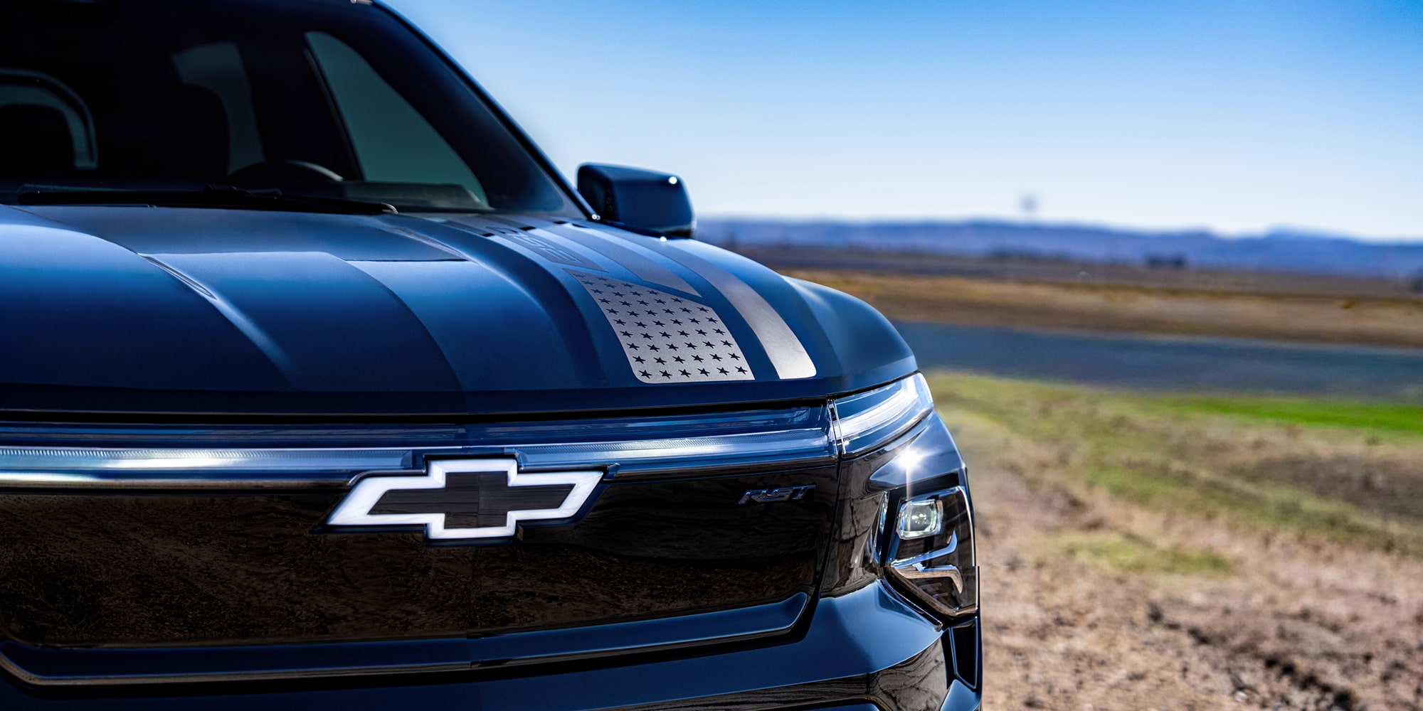 A Close-Up of the Black Chevrolet Silverado EV Front with the Chevrolet Emblem and Hood Stripe.