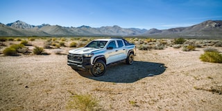 A White Chevrolet Colorado Special Edition Truck Standing on a Dirt Road with Mountains in the Background.