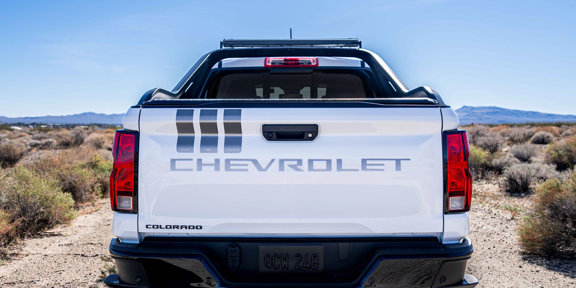 The Rear View of a White Chevrolet Colorado Stars and Steel Truck, Featuring Stripes on the Tailgate.