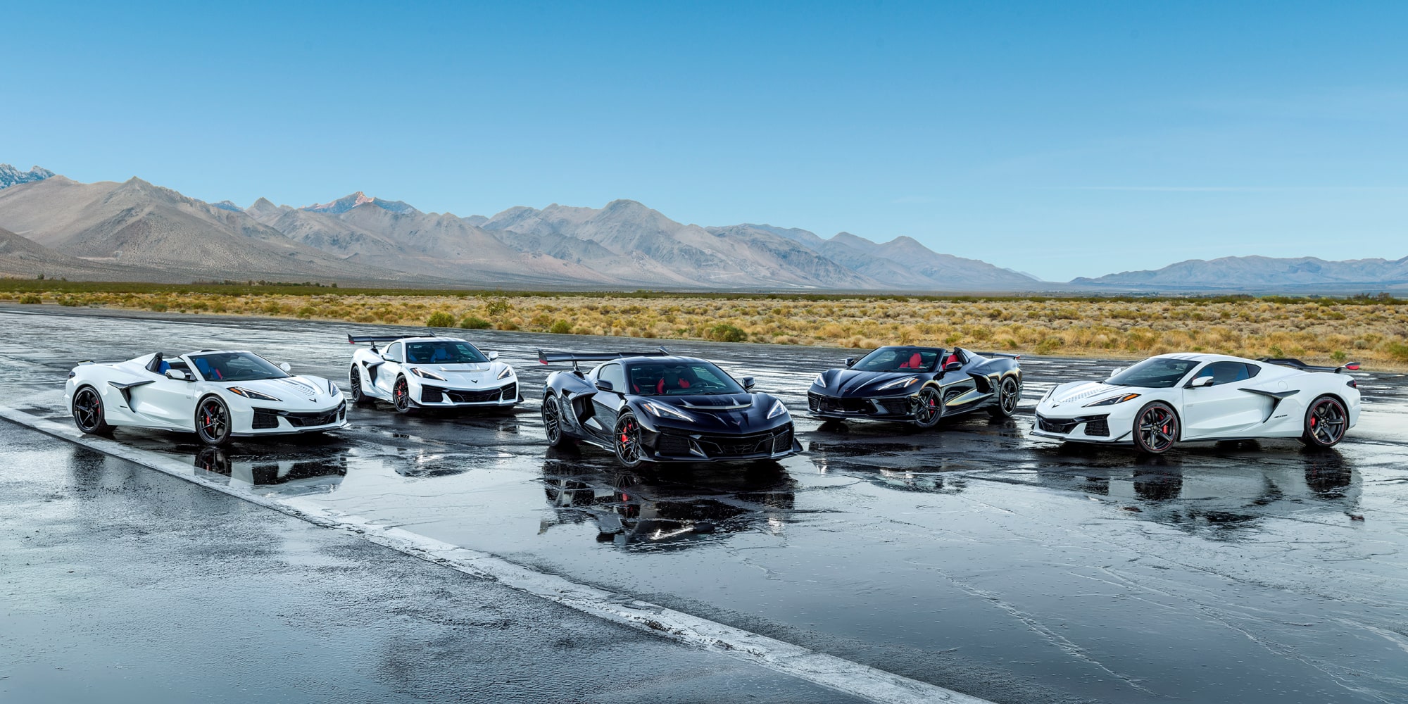 A Collection of Chevrolet Stars and Steel Edition Corvettes on a Wet Surface in a Desert.