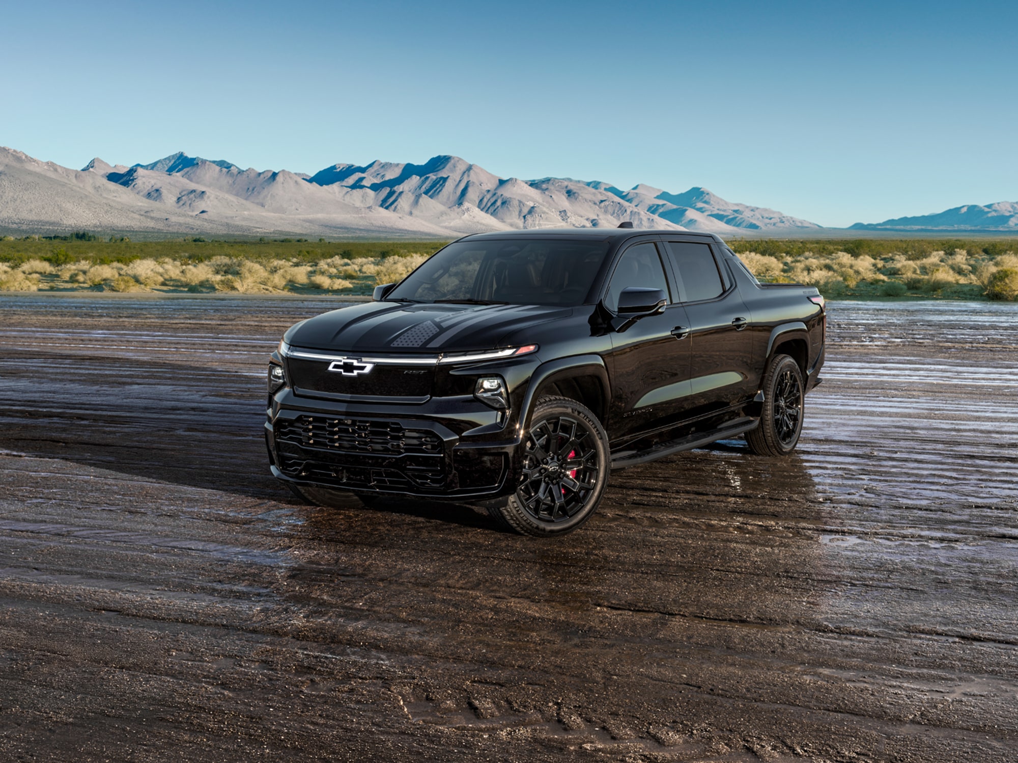 A Black Chevrolet Silverado EV Stars and Steel Edition Truck Parked on a Wet Dirt Road.