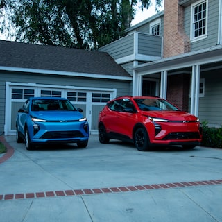 A  2027 Chevrolet Bolt in Mariina Blue Metallic and a 2027 Chevrolet Bolt in Habanero Orange Parking Side by Side in a Driveway.