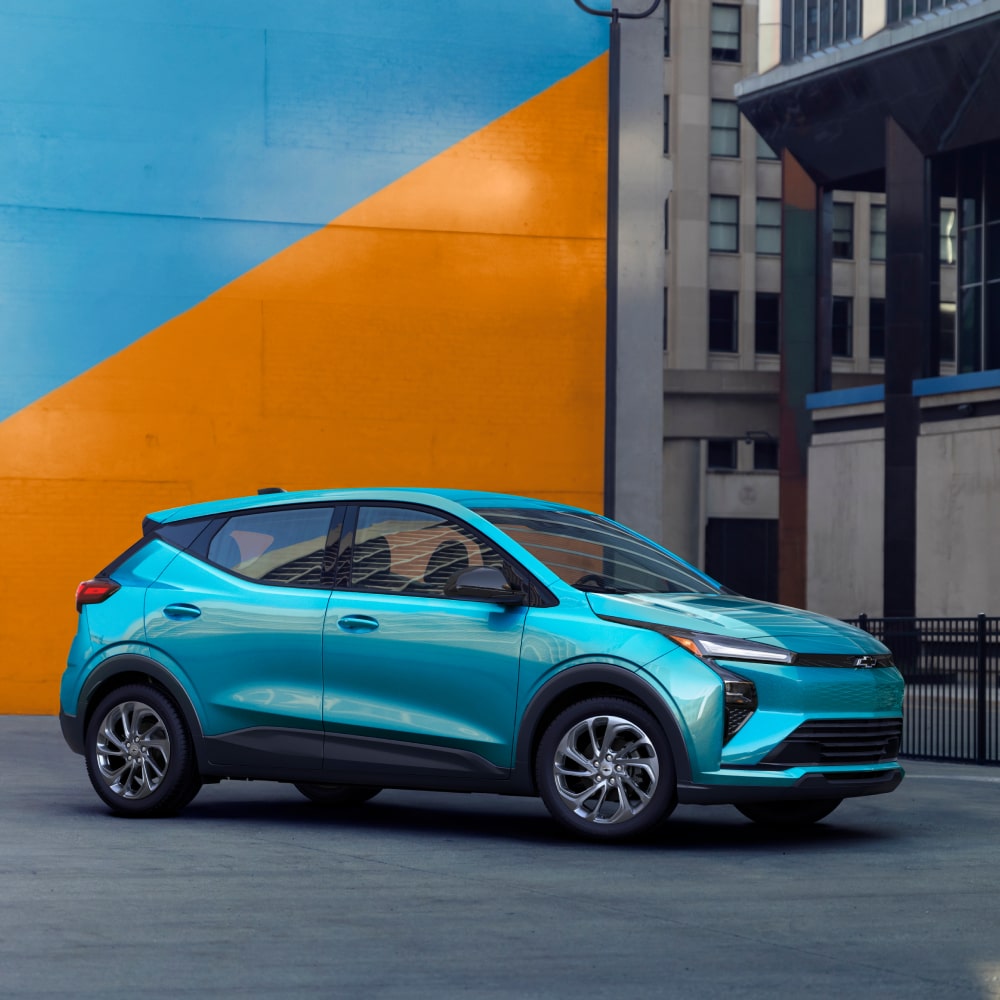 2027 Chevrolet Bolt in Marina Blue Metallic Parked in Front of a Blue and Orange Wall