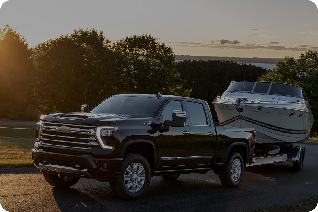 A Dark Colored Chevy Silverado Hauling a Boat Down a Street