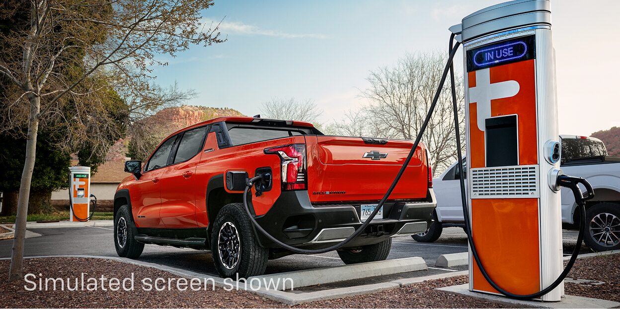 An Orange Chevy Silverado EV Charging at an EV Charging Station