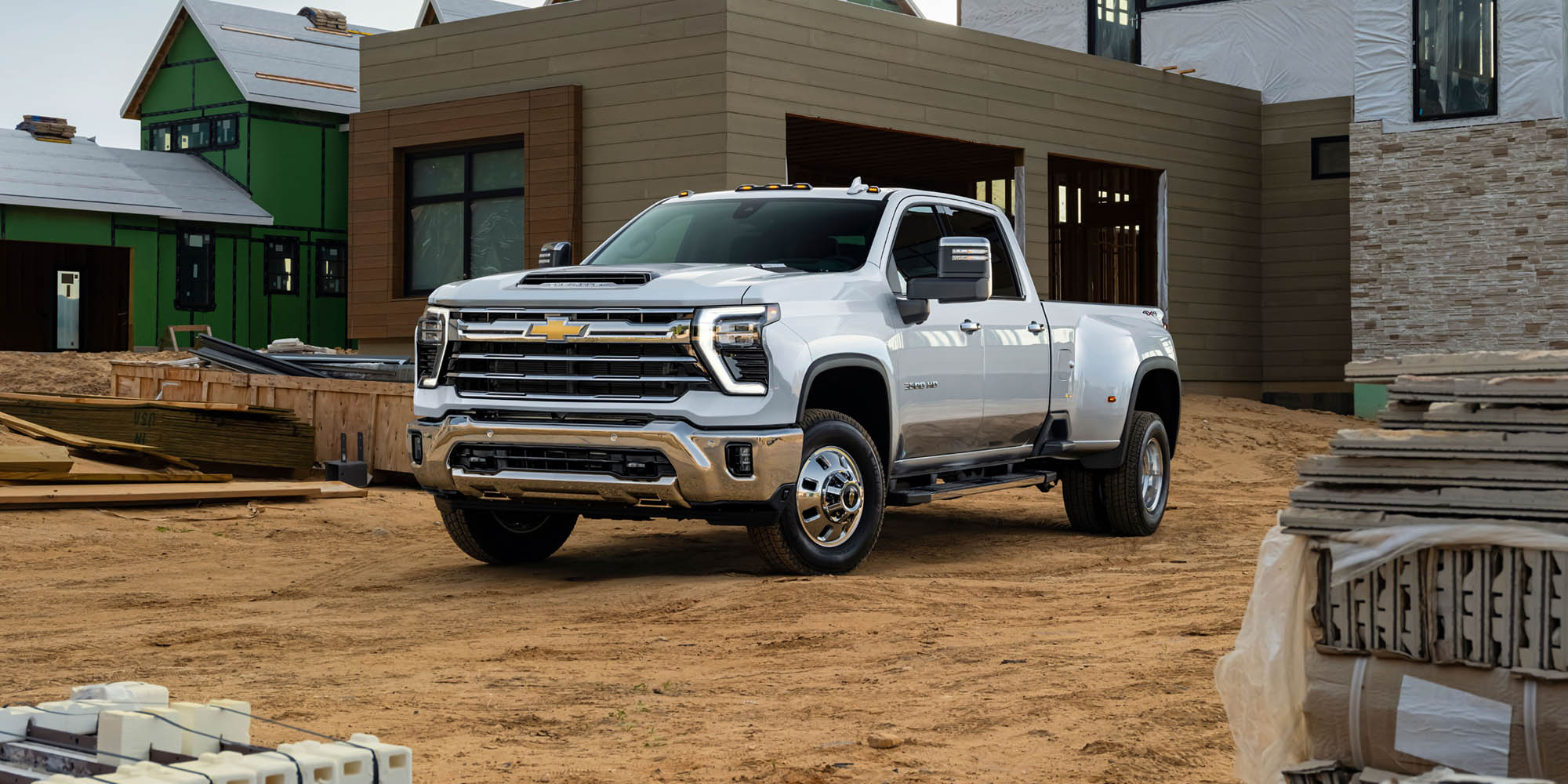Front Three-Quarter View of a White 2026 Chevy Silverado HD Truck in Front of a House