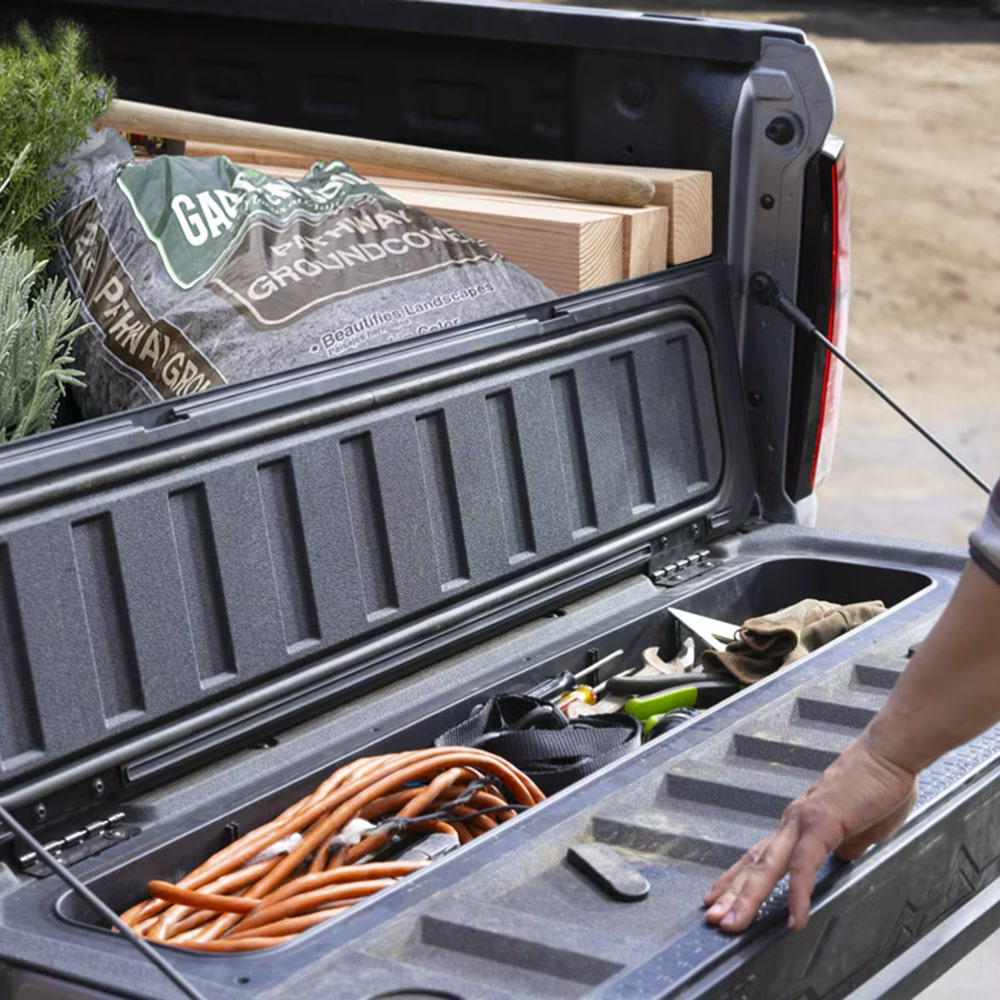 Caja de Chevy Colorado comercial donde se muestra el compartimiento de almacenamiento de la puerta trasera con herramientas y equipo de trabajo organizado adentro.