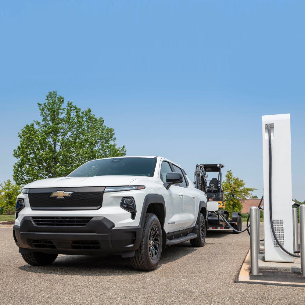 2027 Chevy Commercial Silverado EV Towing Construction Equipment While Parked at a Charging Station