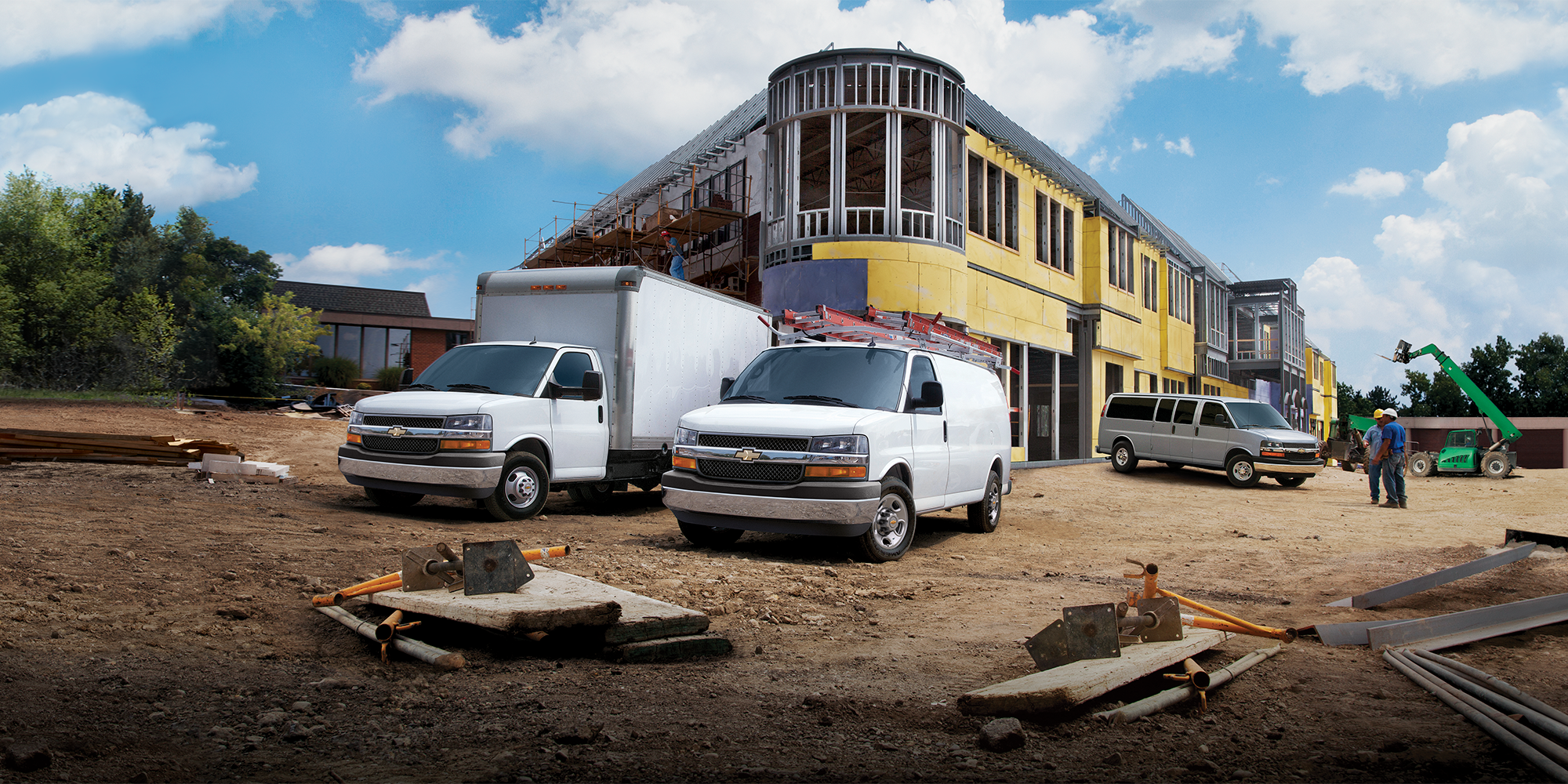 Three Chevrolet Express Cutaway Vehicles on a Construction Site, Including a Box Truck, a Utility Van, and a Passenger Van.