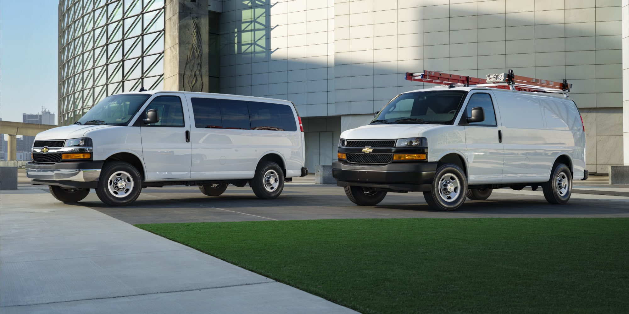 2026 Chevy Commercial Express Vans Parked Outside Glass Office Building
