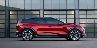 A Red Chevrolet Blazer EV Parked in Front of a Modern Building With Large Glass Panels and a Gray Exterior Wall.