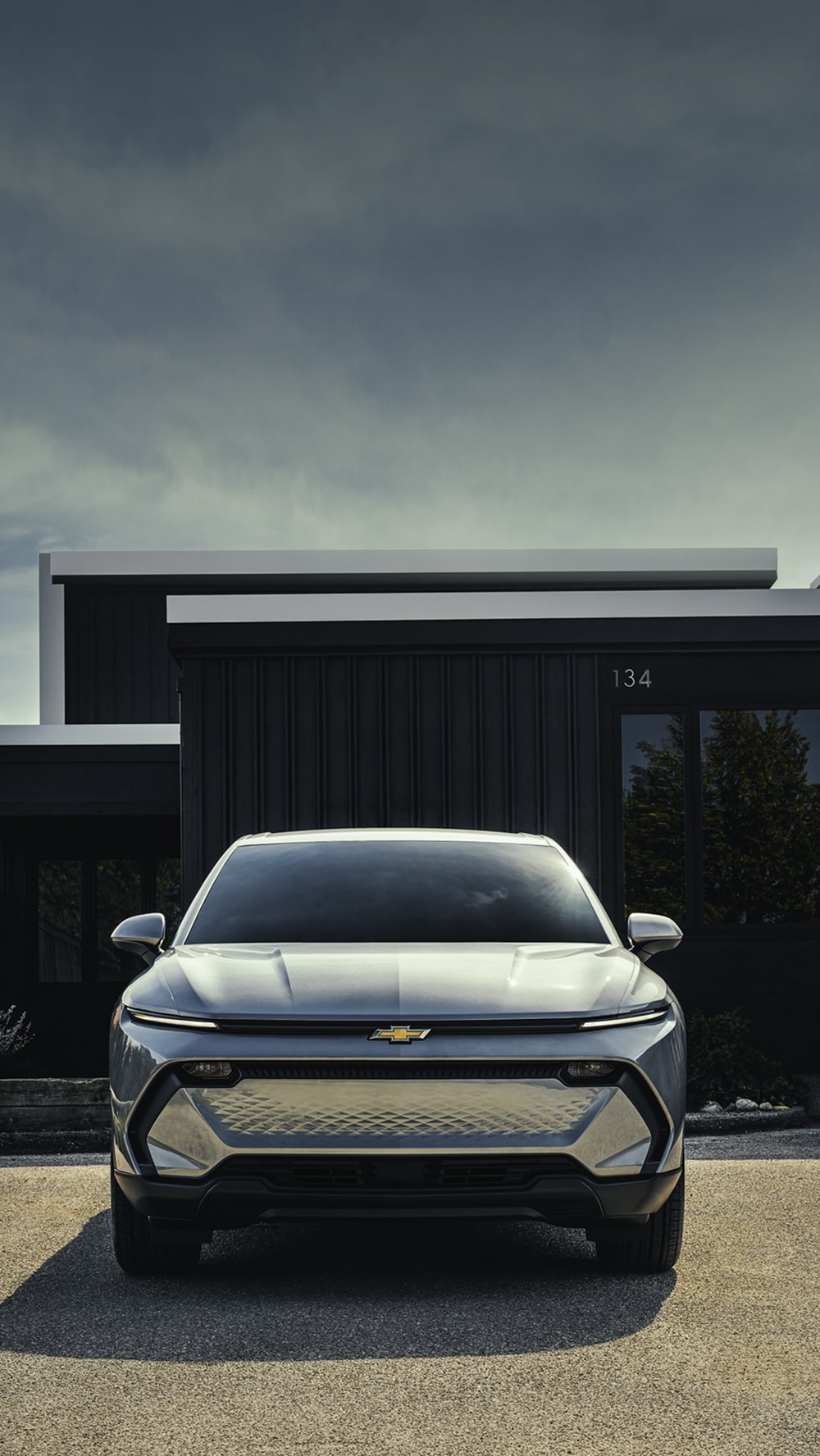 A Silver Chevrolet Equinox EV Parked in Front of a Modern Dark Building.