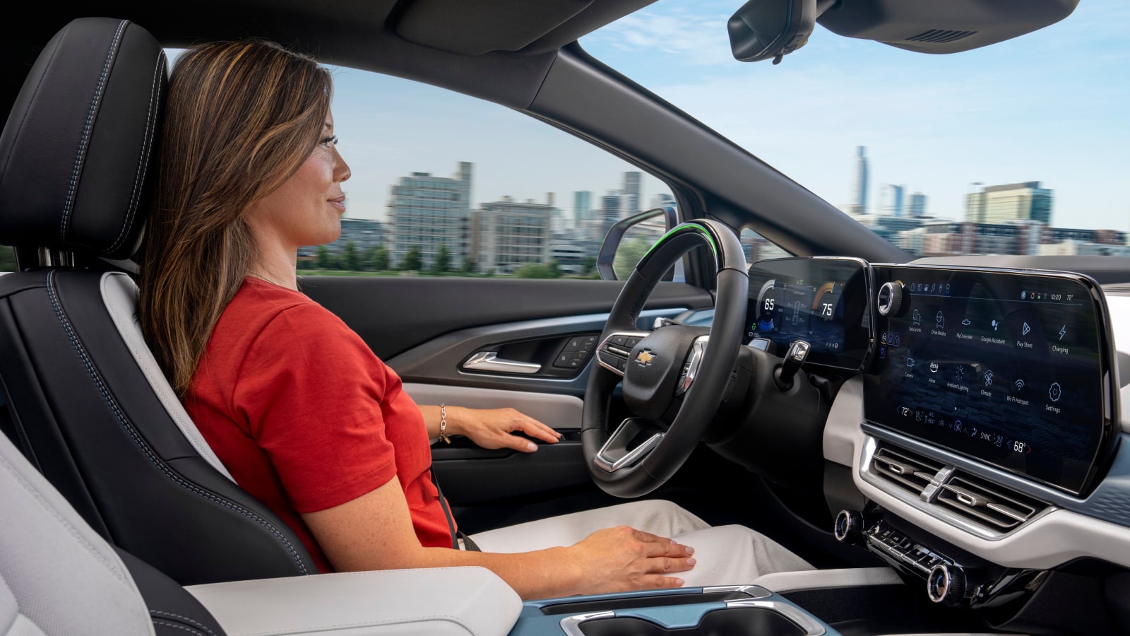 A Silver Chevrolet Equinox EV Driving on a Road Next to a Body of Water and Trees on a Sunny Day.