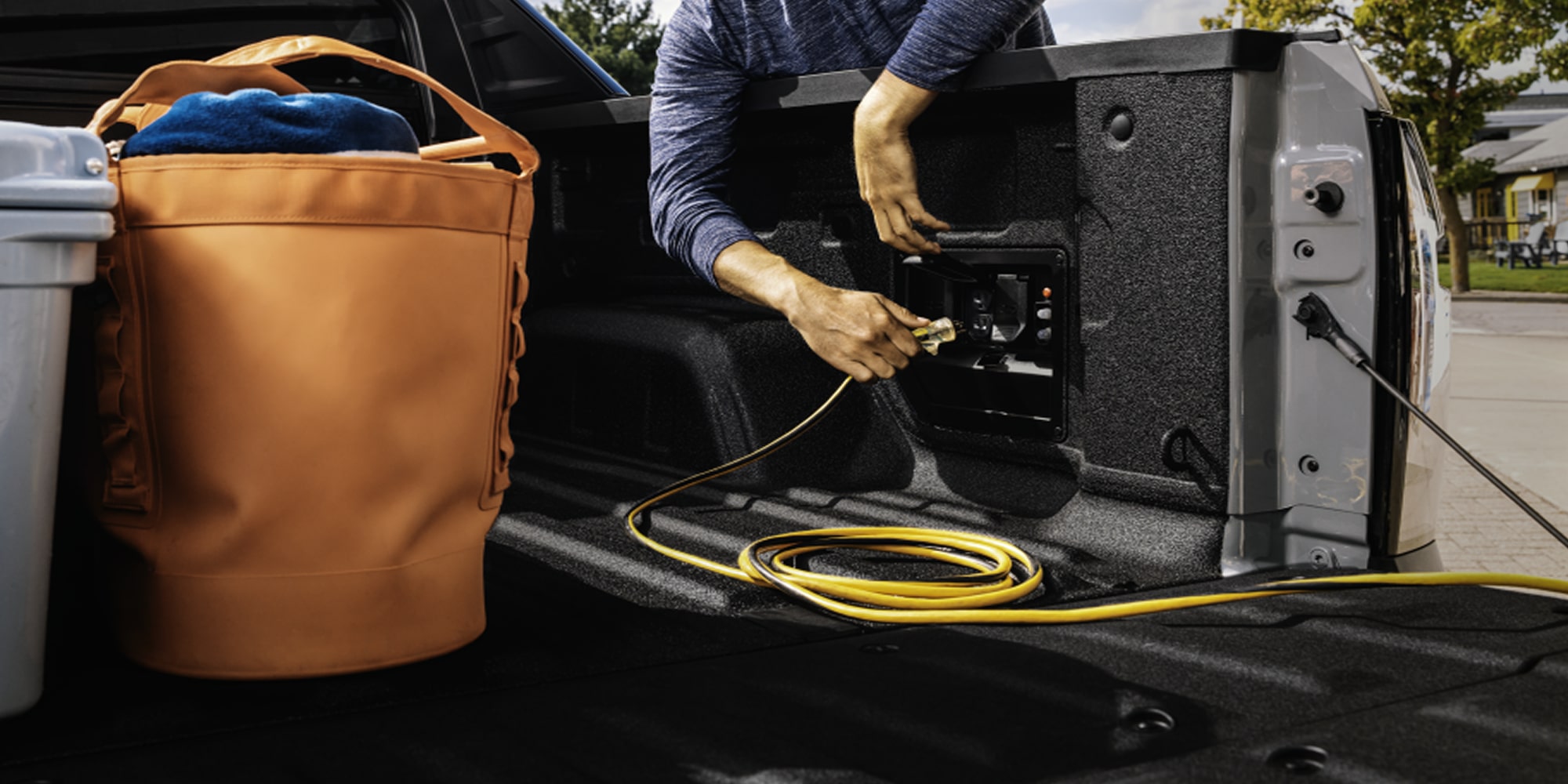 A Man Pulling an Extension Cord into the Bed Outlet of the 2026 Chevy Silverado EV