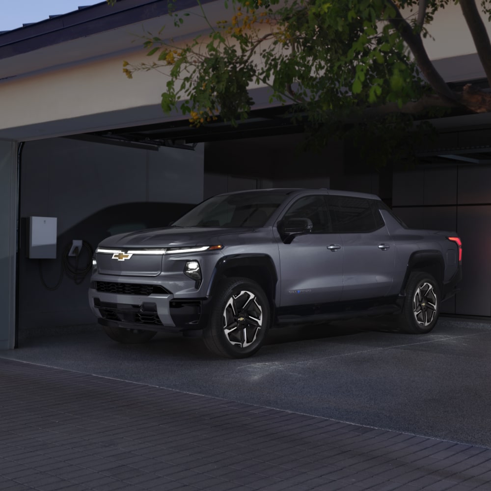 2026 Chevy Silverado EV Parked in a Garage Next to a Home Charging Station