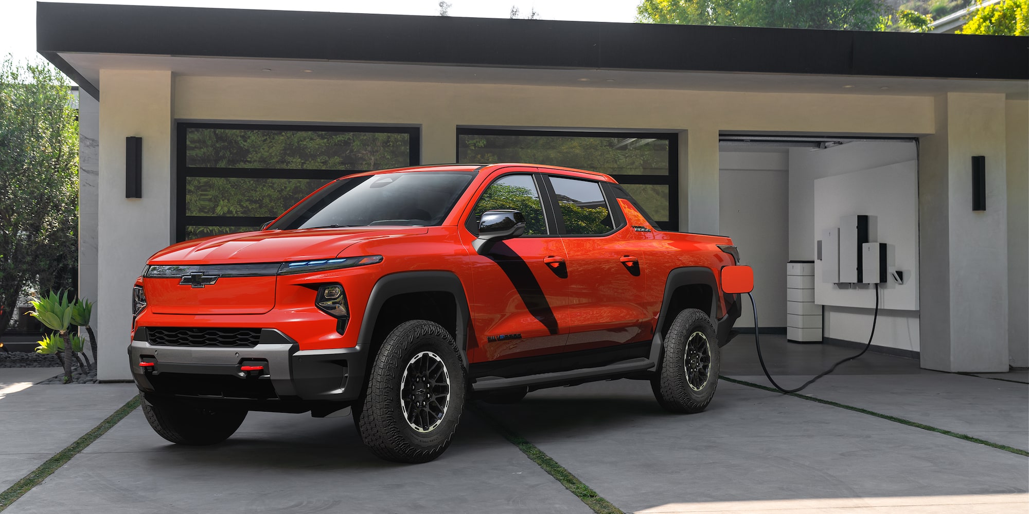 2026 Chevy Silverado EV Parked in a Garage Next to a Home Charging Station