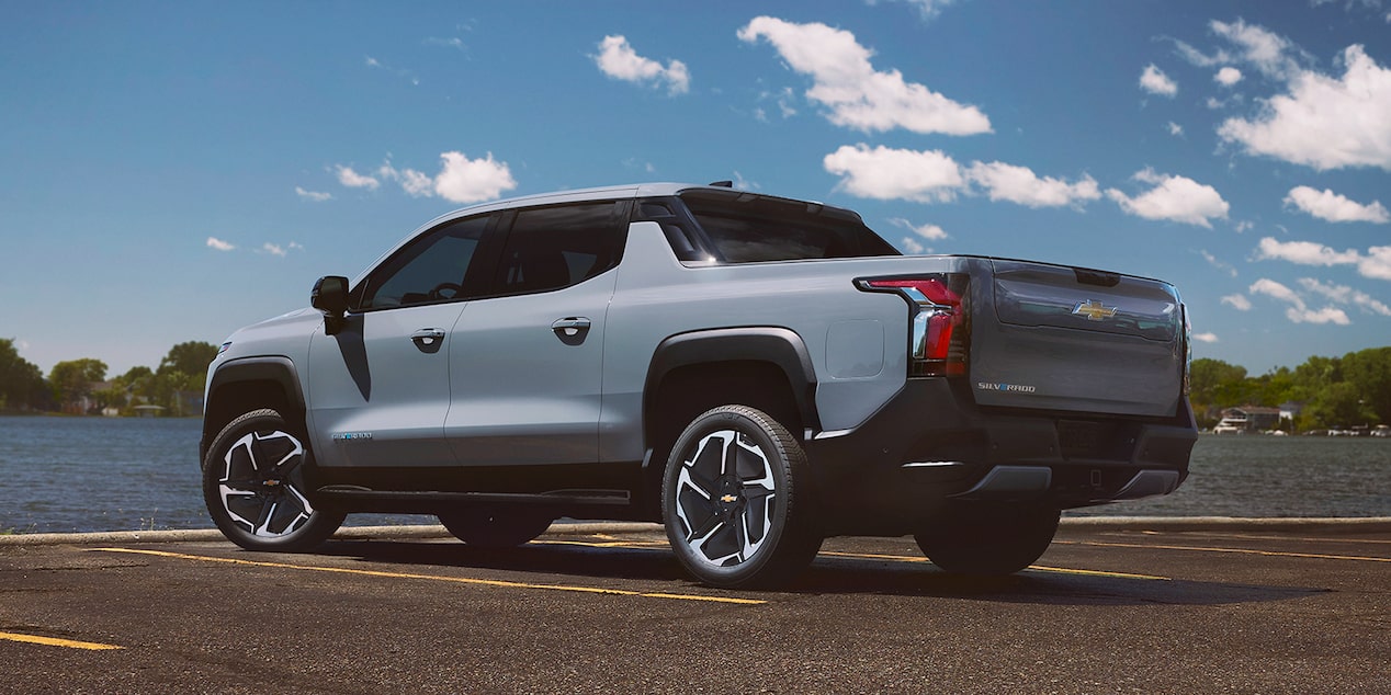 Three Quarters Rear View of a 2026 Chevy Silverado EV in Front of a Body of Water on a Sunny Day