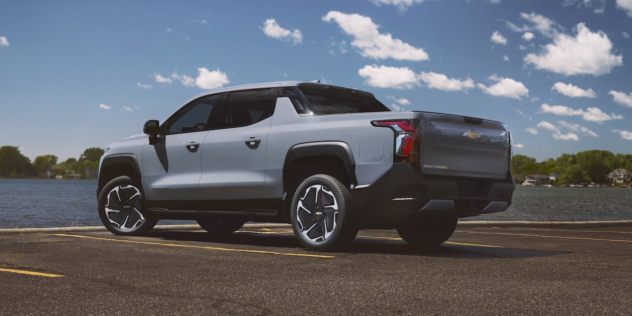 Three Quarters Rear View of a 2026 Chevy Silverado EV in Front of a Body of Water on a Sunny Day