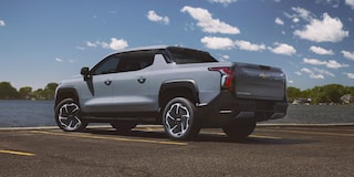 Three Quarters Rear View of a 2026 Chevy Silverado EV in Front of a Body of Water on a Sunny Day