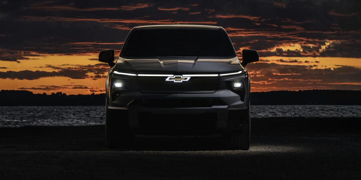 Front View of a 2026 Chevy Silverado EV on the Right Side of the Frame with Its Lights on in Dark Just after Sunset
