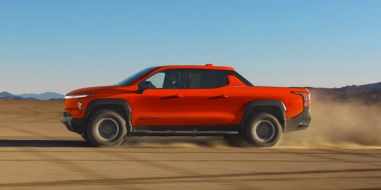 Side View of an Orange 2026 Chevy Silverado EV Driving Down the Desert