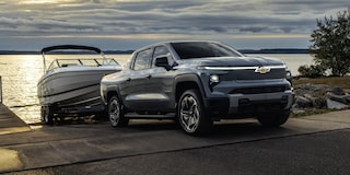 Three Quarters View of a 2026 Chevy Silverado EV Pulling Out a Speed Boat of the Shores of a Body of Water at Evening