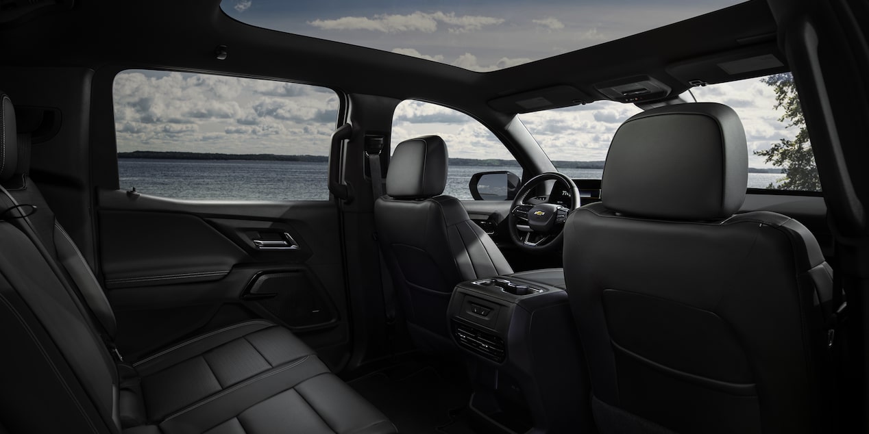 Three Quarters View of the Full Interior of a 2026 Chevy Silverado EV Next to a Body of Water under a Cloudy Sky