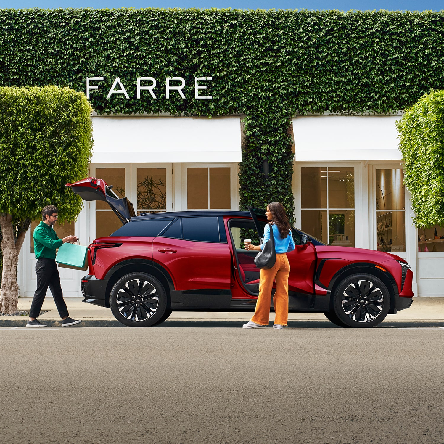 A 2027 Chevy Blazer EV RS Parked in a Residential Driveway With the Rear Liftgate Open, Showcasing Cargo Loading Capability Beside a Modern Home.