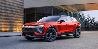 A 2027 Chevy Blazer EV SS Parked Outside a Modern Building Featuring Black Alloy Wheels, Distinctive LED Lighting, a Contrasting Roof, and Athletic Exterior Styling Viewed From a Front Three-Quarter Angle.