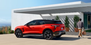 Side Profile View of the 2027 Chevy Blazer EV SS Parked Under an Awning With a Man Walking Towards a House.