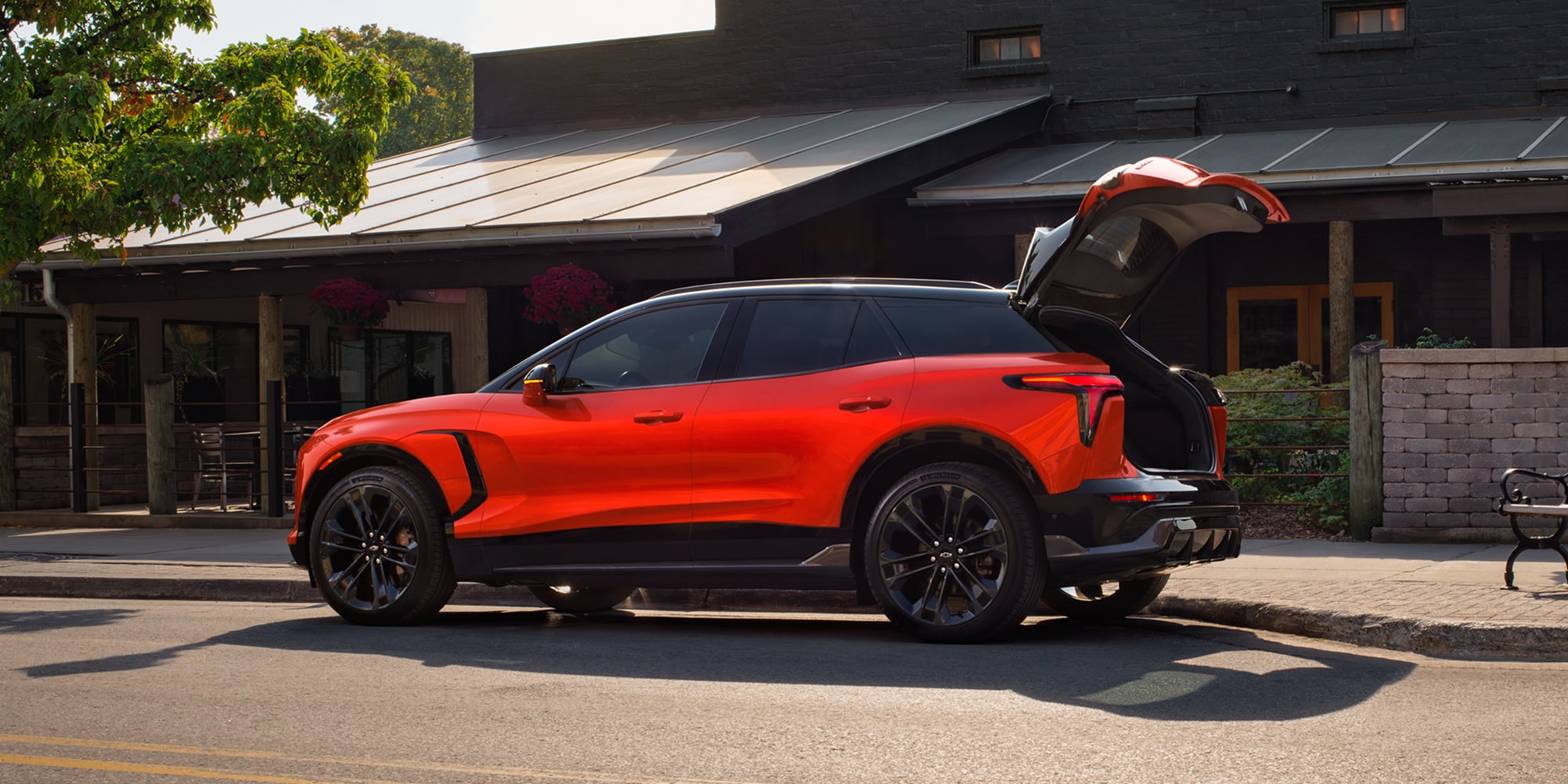 A 2027 Chevy Blazer EV SS Parked in a Residential Driveway With the Rear Liftgate Open, Highlighting Flexible Cargo Access and Spacious Storage Capability.