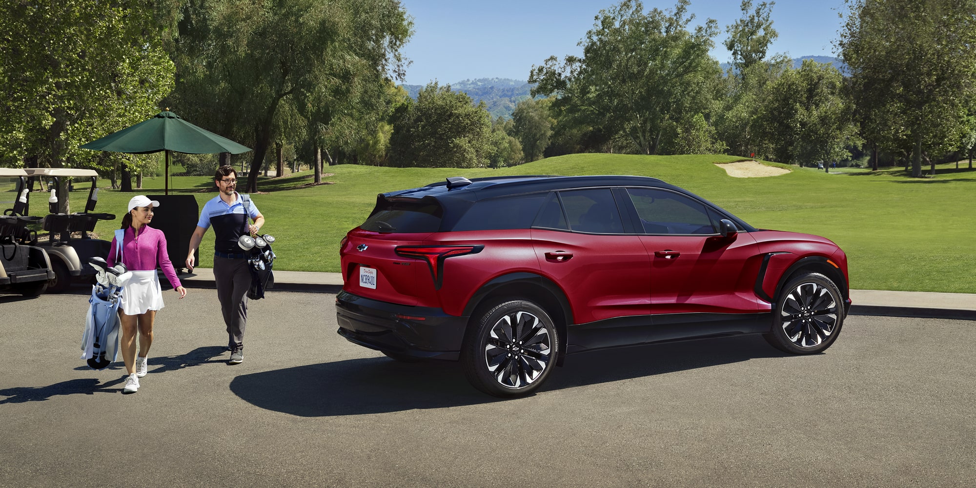 A 2027 Chevy Blazer EV RS Parked Near a Golf Course With Sleek Body Lines, LED Taillights, and Black Alloy Wheels Visible From a Rear Three-Quarter Angle.