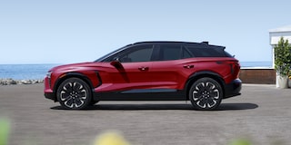 A 2027 Chevy Blazer EV RS Parked Near a Coastal Setting Showcasing a Sporty Side Profile, Black Alloy Wheels, and Sculpted Exterior Design.