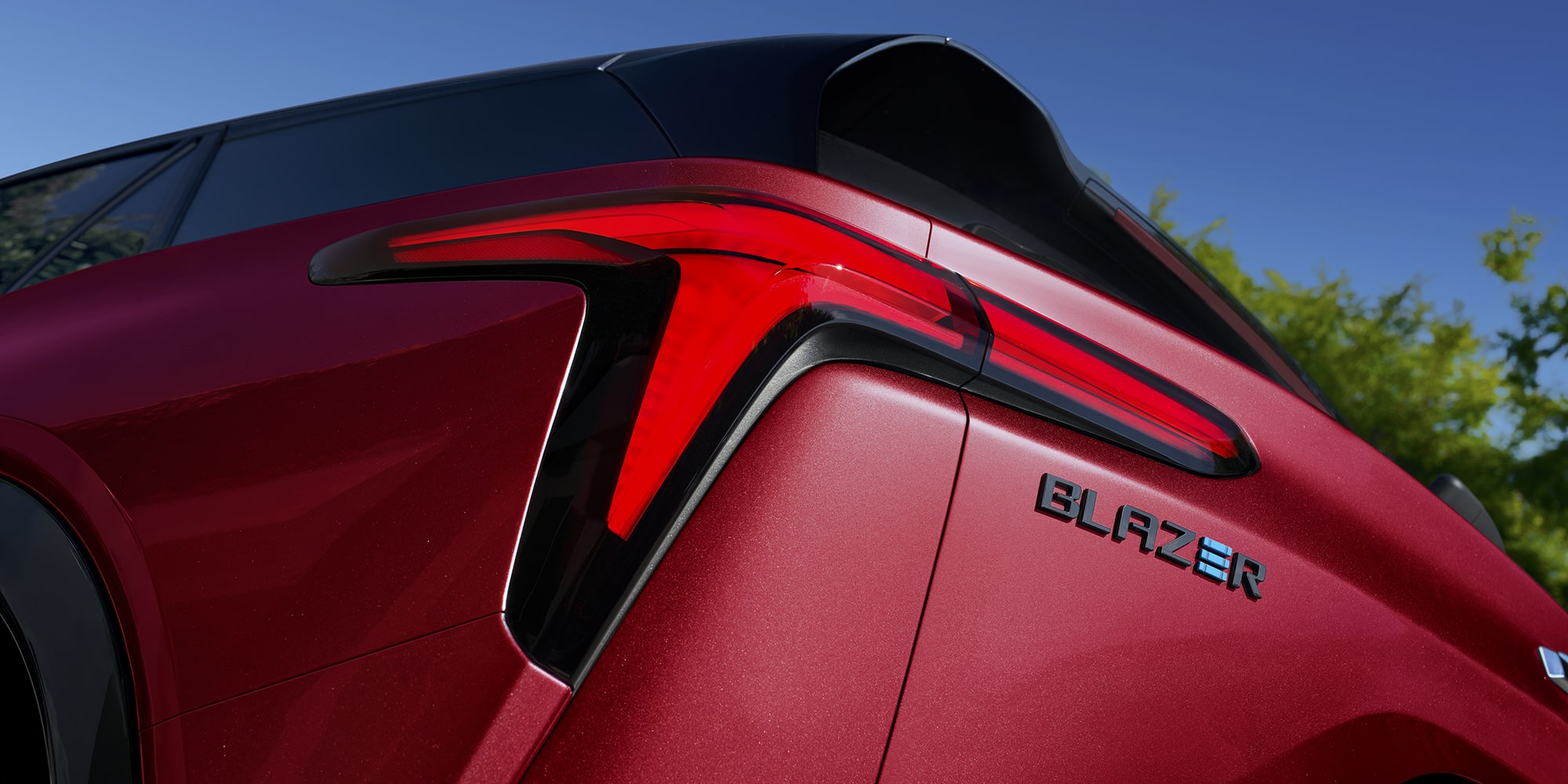 A Close-Up View of the Rear Quarter Panel of a 2027 Chevy Blazer EV RS Featuring a Distinctive LED Taillight Design, Integrated Rear Spoiler, and Blazer Badging.