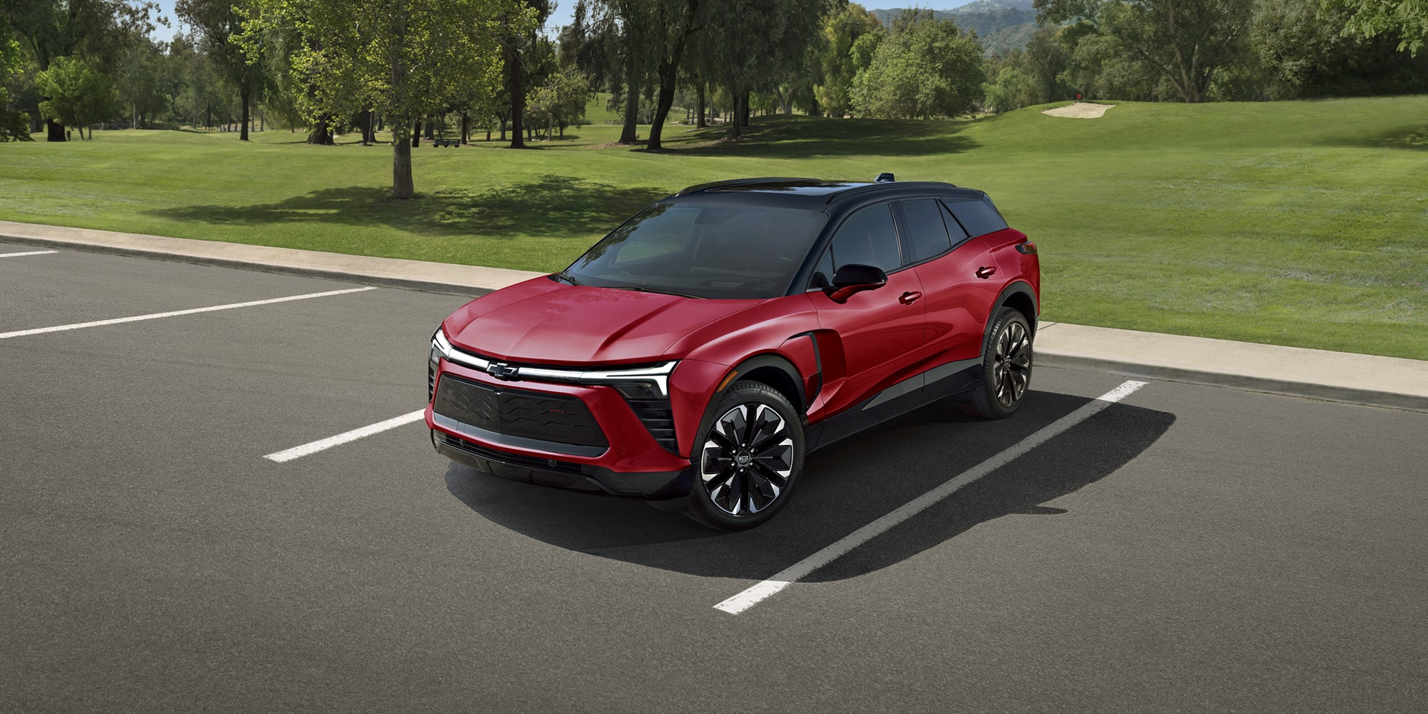 A 2027 Chevy Blazer EV RS Parked in an Outdoor Lot Showcasing Black Alloy Wheels, Athletic Body Lines, and Distinctive Front-End Styling From a Front Three-Quarter View.