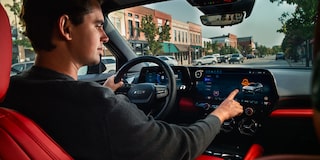 A Driver Interacting With the Infotainment Touchscreen Inside a 2027 Chevy Blazer EV SS Featuring Premium Interior Accents, Digital Displays, and a Modern Driver-Focused Cabin.
