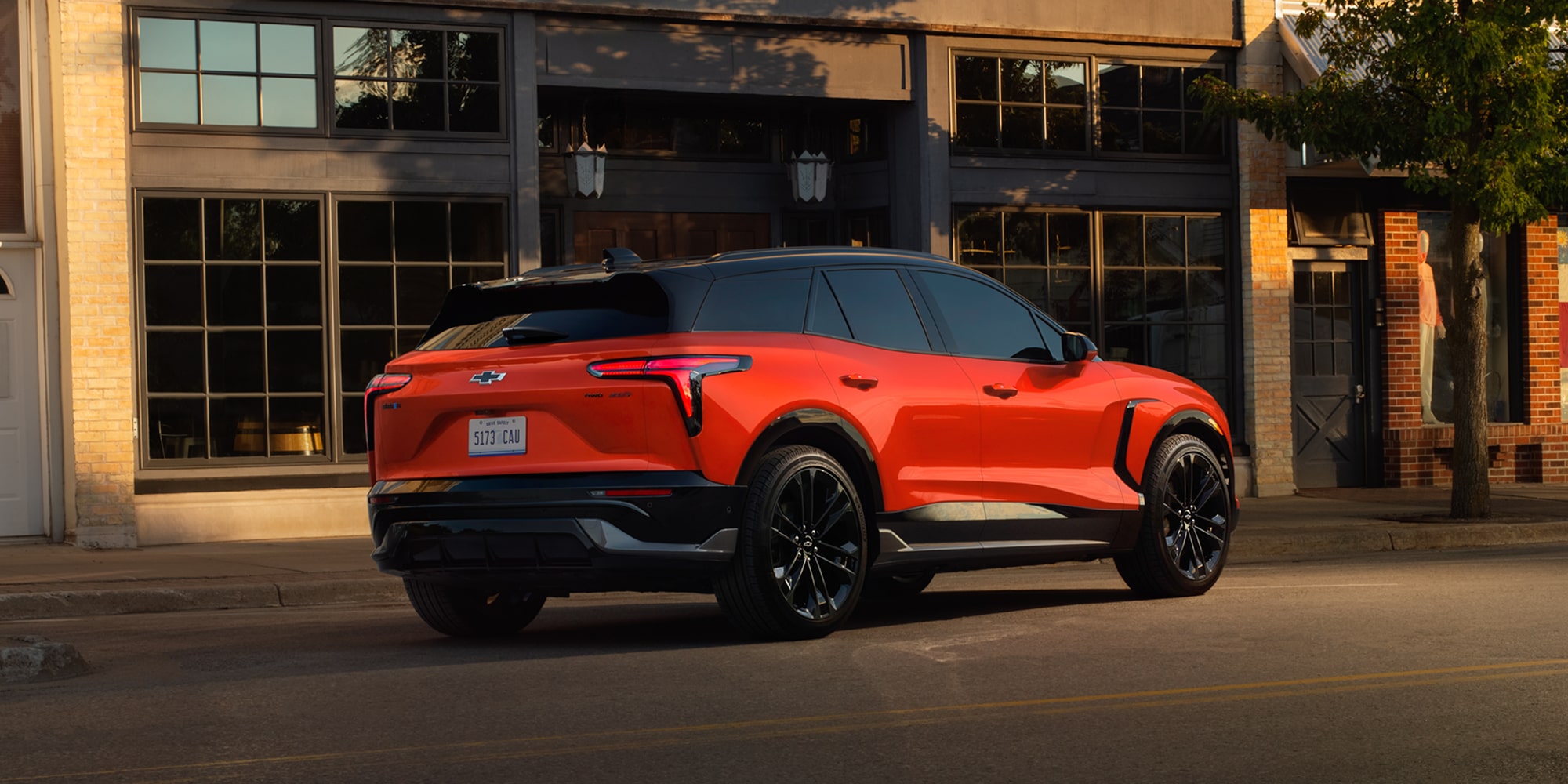 A 2027 Chevy Blazer EV Parked Along an Urban Street With Black Alloy Wheels, LED Taillights, and Sculpted Body Lines Visible From a Rear Three-Quarter Angle.