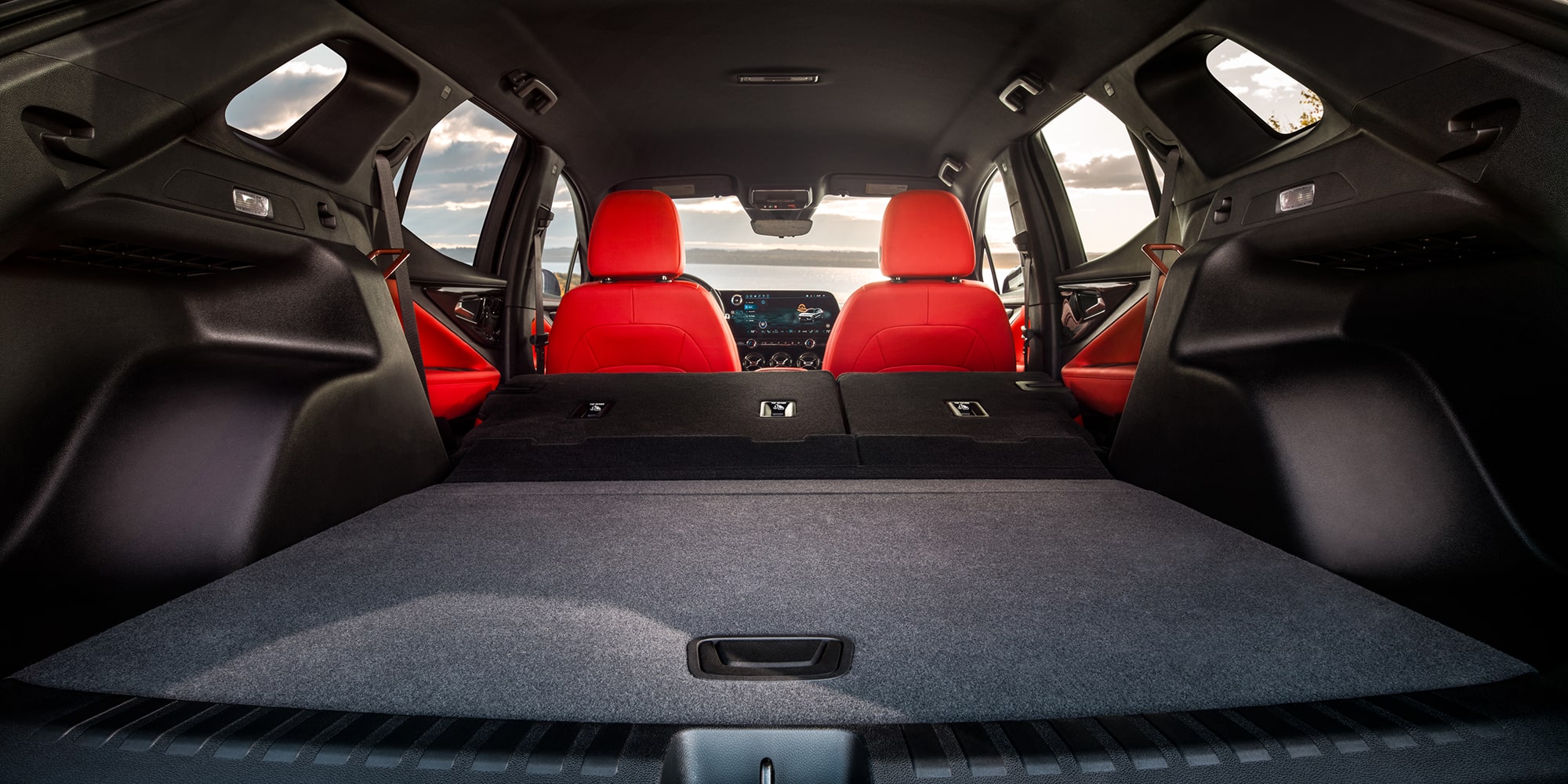 The Cargo Area of a 2027 Chevy Blazer EV Featuring a Flat Load Floor, Folded Rear Seats, Red Seatbacks, and Spacious Storage Capacity Visible From the Rear Hatch Opening.