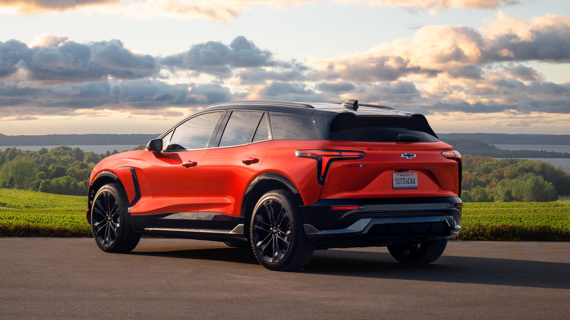 A 2027 Chevy Blazer EV Parked on a Scenic Overlook With Rolling Green Hills Visible From a Rear Three-Quarter Angle.