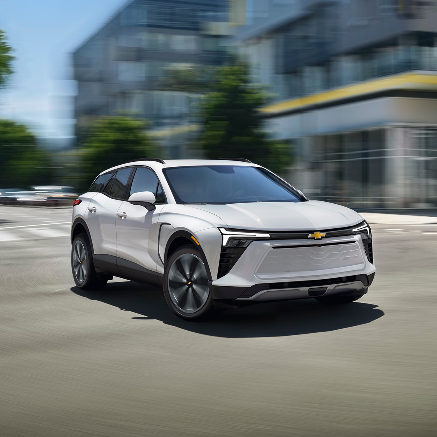 A 2027 Chevy Blazer EV Driving on a City Street With LED Lighting Elements and Large Multi-Spoke Alloy Wheels.